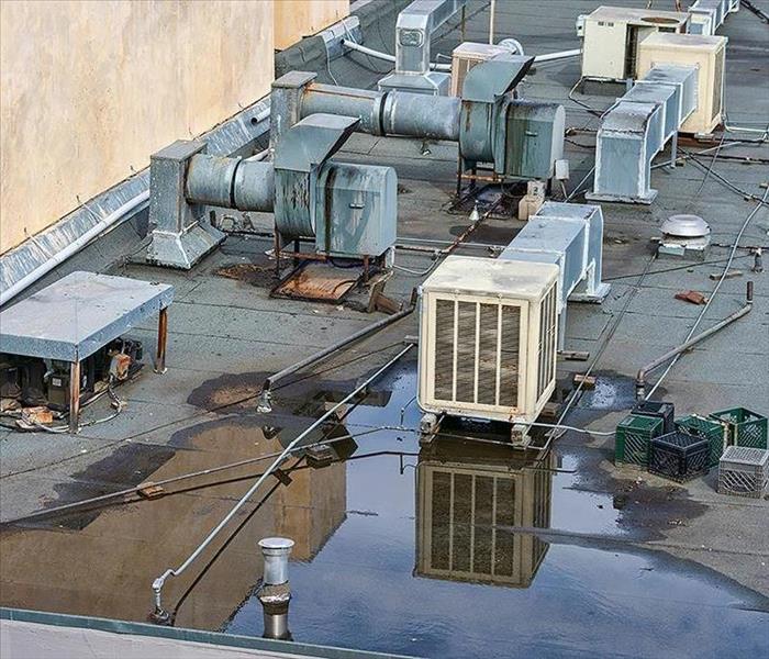 roof top with metal ac heating units with water surrounding them