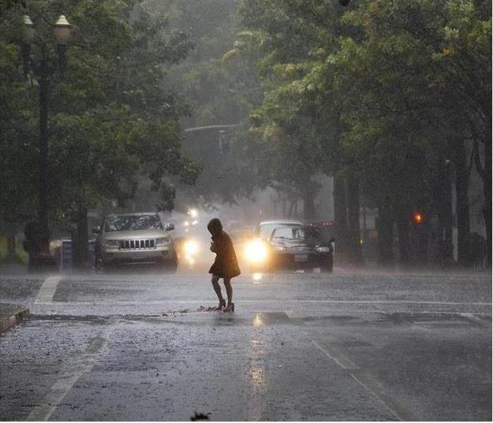 women walking in rain in street with cars in the background