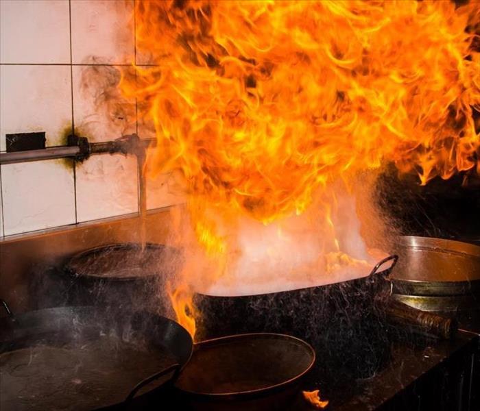 Stove with pot that is on fire with tile backround